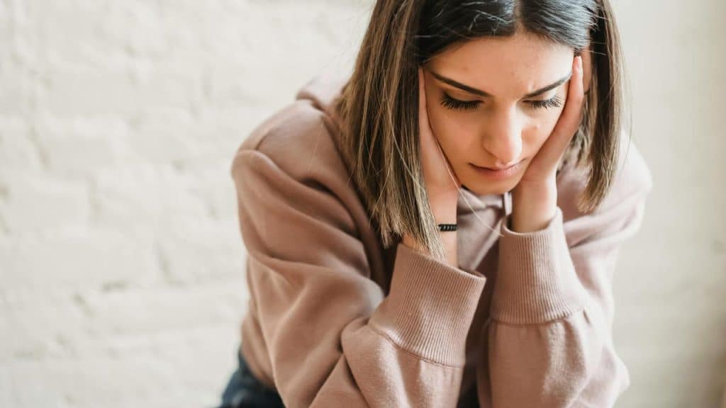 A woman sitting with her head in her hands looking down.