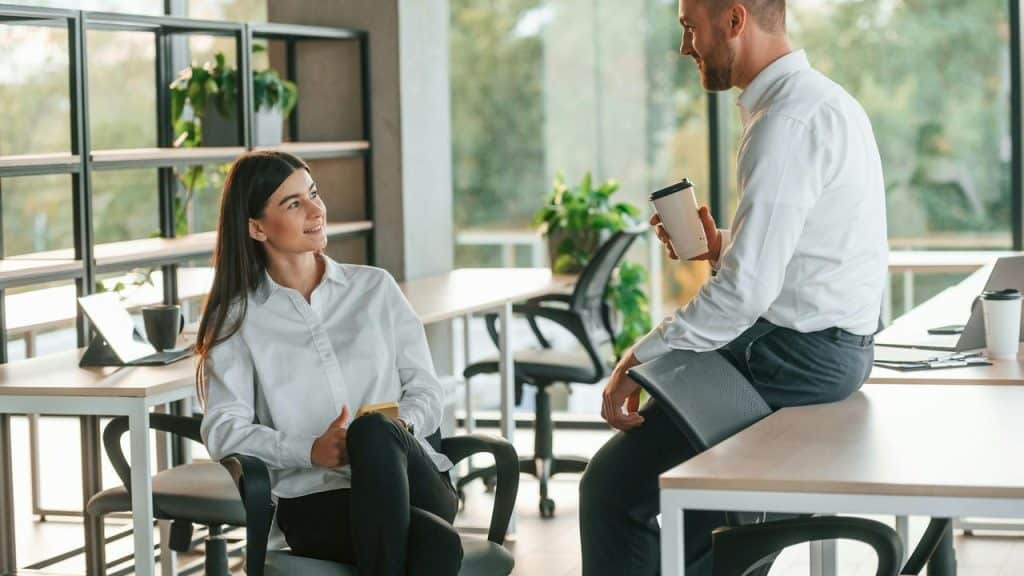 A man and woman having a conversation in an office setting.