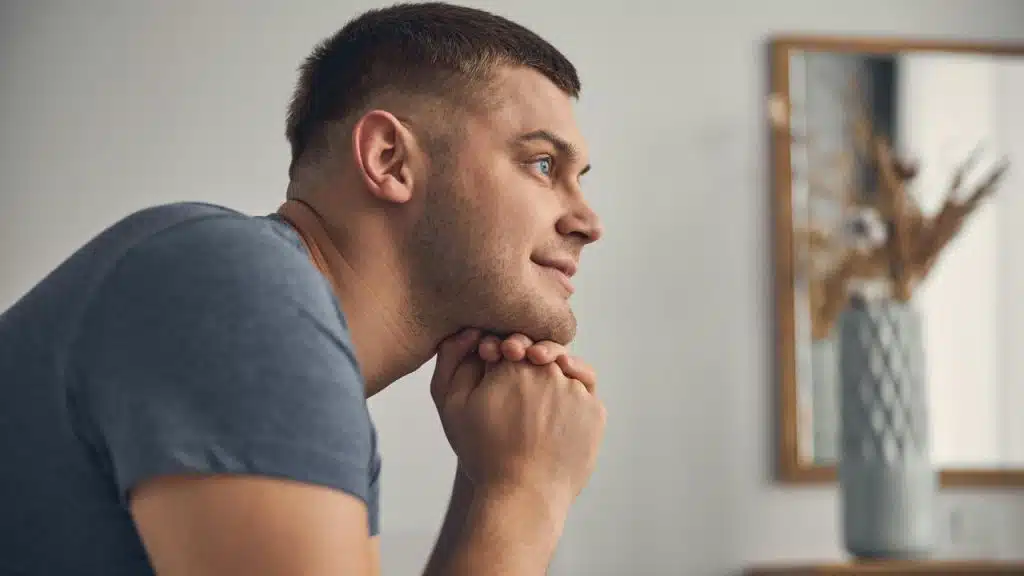 A man resting his chin on his hands with a thoughtful expression.