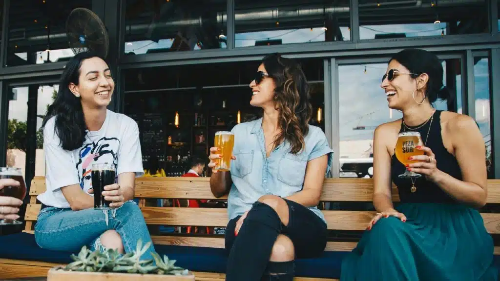 A group of friends laughing and enjoying drinks at an outdoor bar.