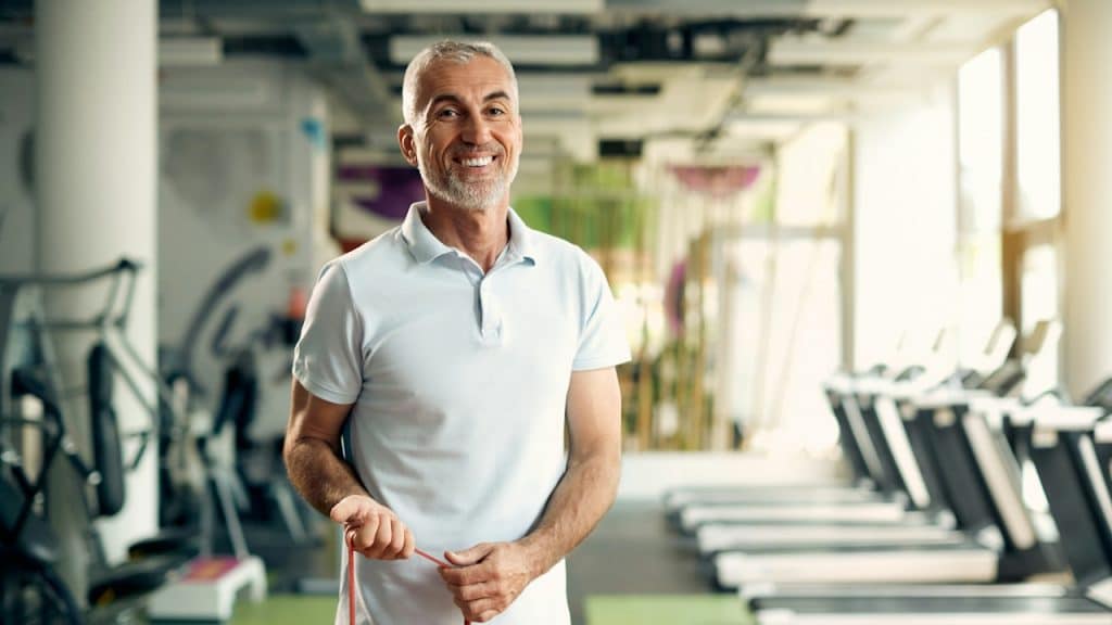 A man smiling and working out in a gym.