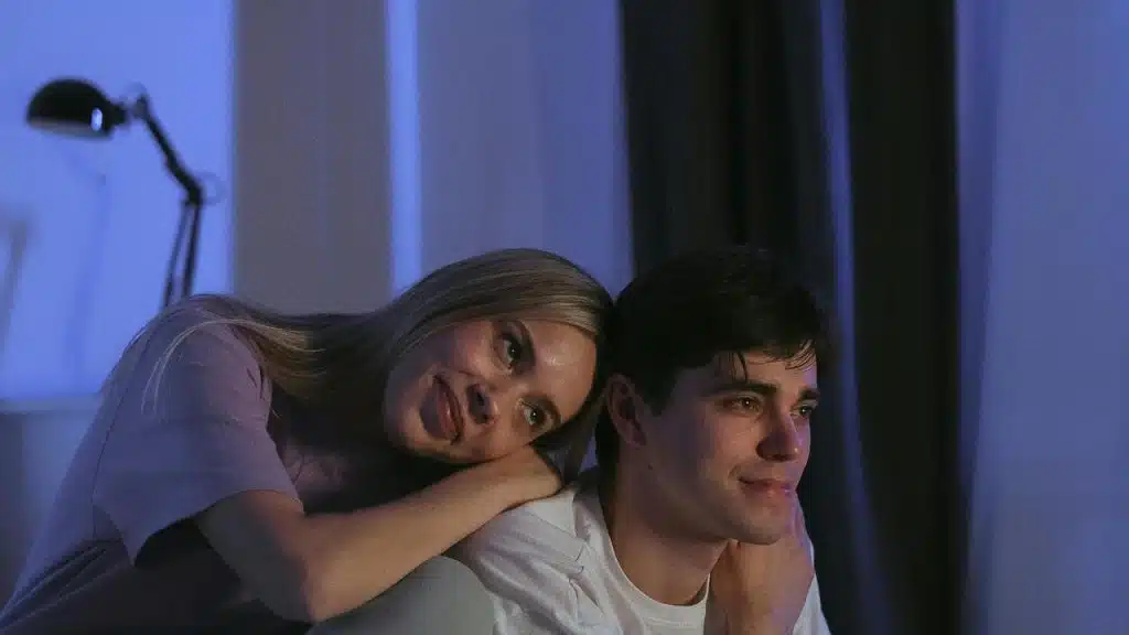 A couple sitting closely together with the woman resting her head on the man’s shoulder.