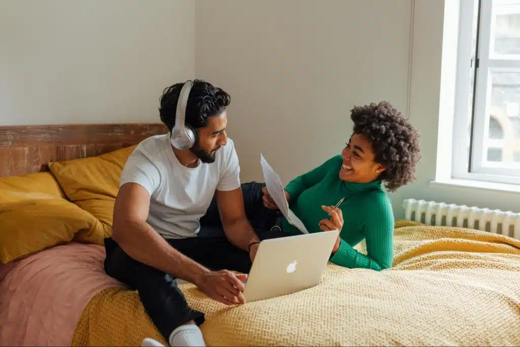 A man using a laptop and a woman reading a document