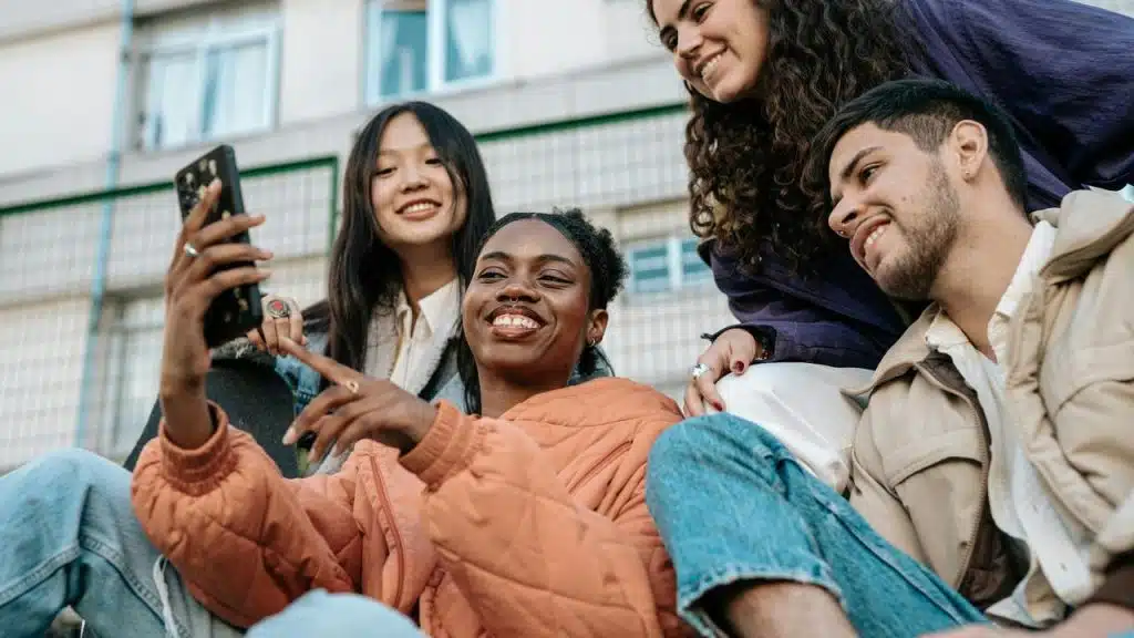A group of friends smiling and taking a selfie outdoors.