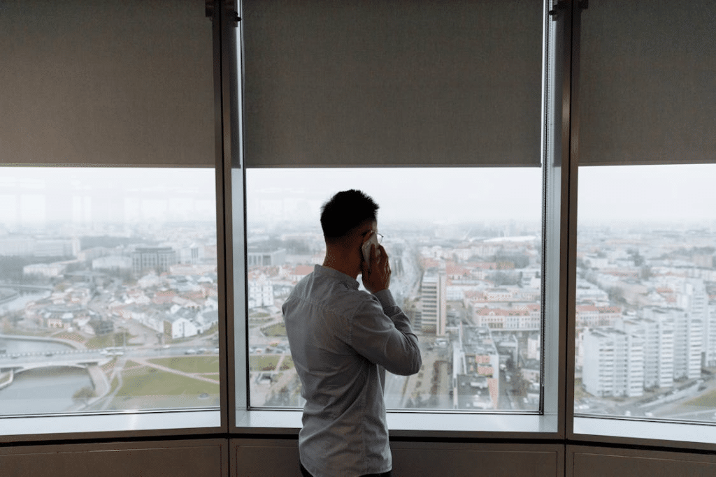 A Man Talking on Phone While Standing In Front of a Glass Window