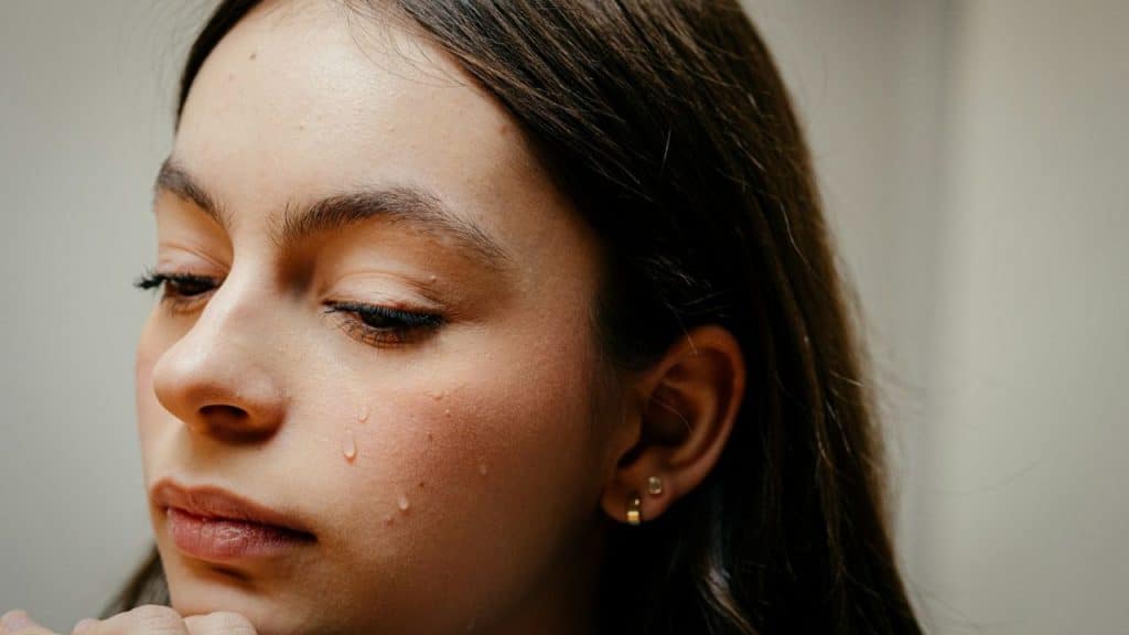 Close-up of a crying woman with a tear running down her cheek.
