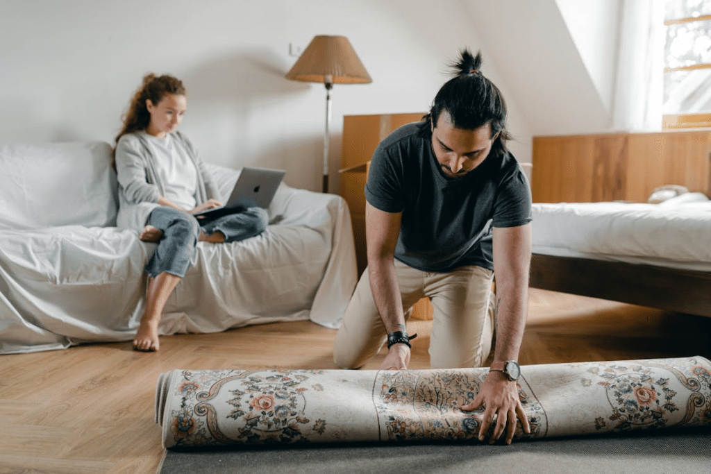 A man rolling a carpet on the floor