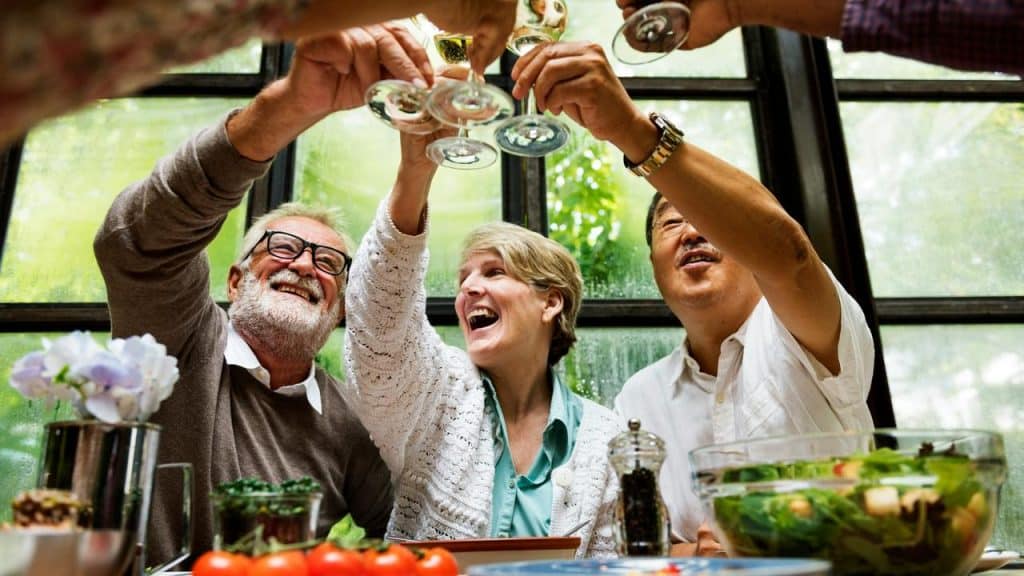 A group of senior people clinking their glasses on a dinner table.