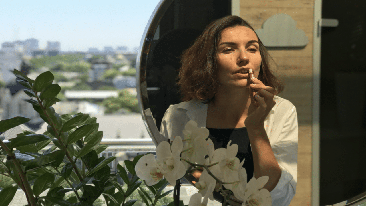 A woman reapplying lip gloss in public