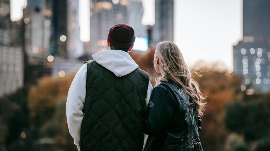 A couple standing outside and looking out toward city buildings.