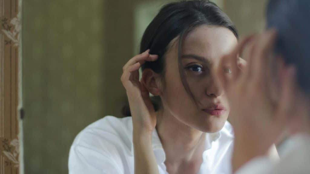 A woman adjusting her hair in front of a mirror.