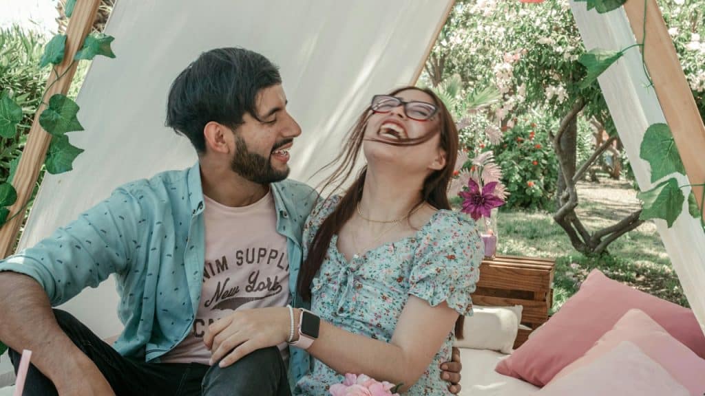 A man and a woman sitting on a couch laughing.