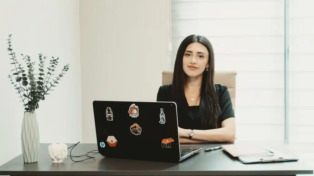 A woman sits at a desk with a laptop.