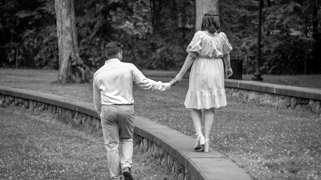 A man walking hand in hand with a woman who is walking on an elevated path from the ground level.