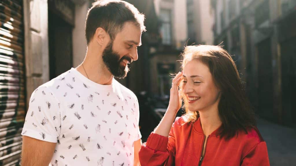 Smiling couple on a sunny street, the woman touching her hair.