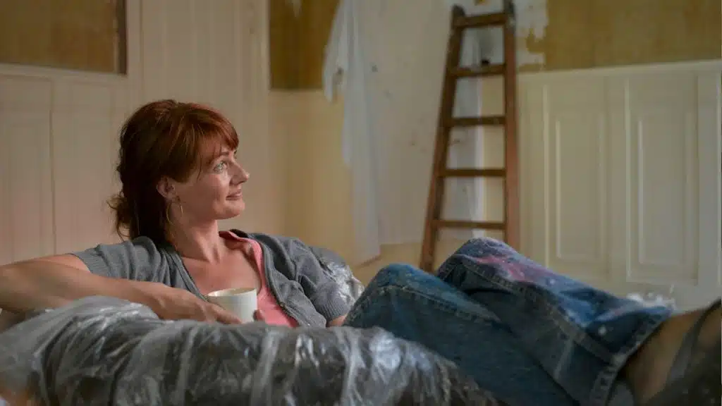 A woman sitting on a new couch with a cup of coffee.