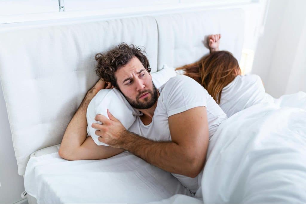 A man overthinking and a woman sleeping