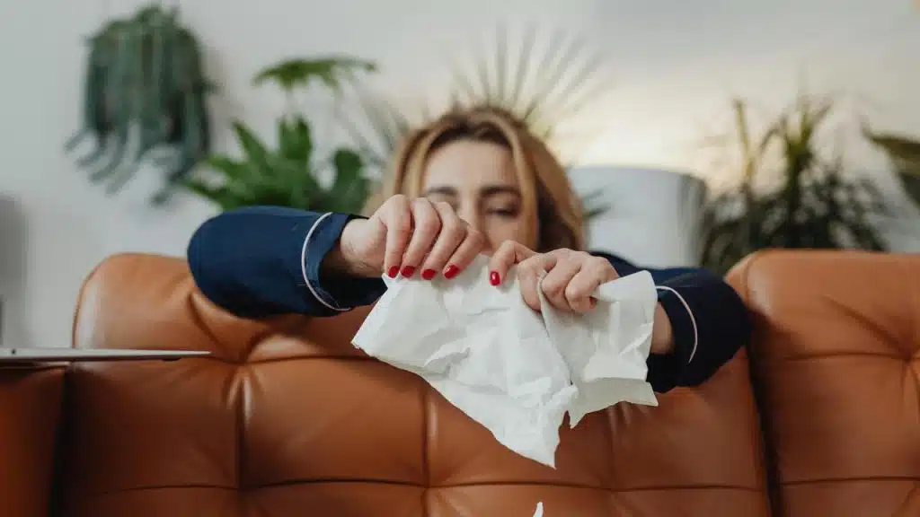 A woman tearing a piece of paper while sitting on a couch.