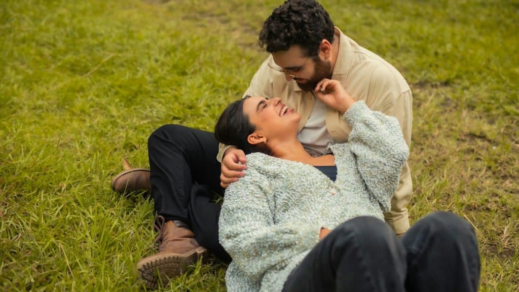 A couple talking, laughing, and lying in the grass.