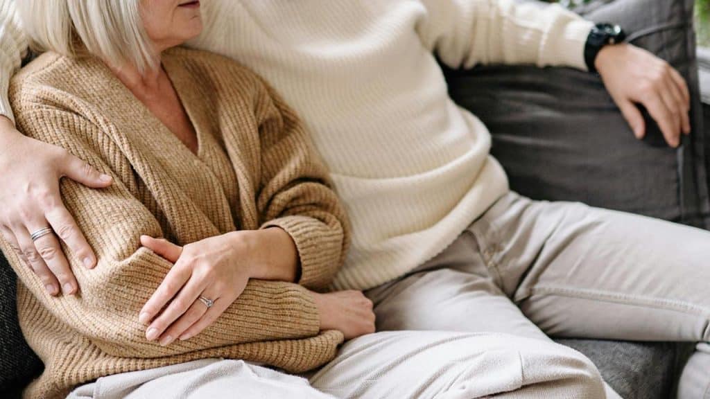A close-up of an older couple cuddling on a couch.