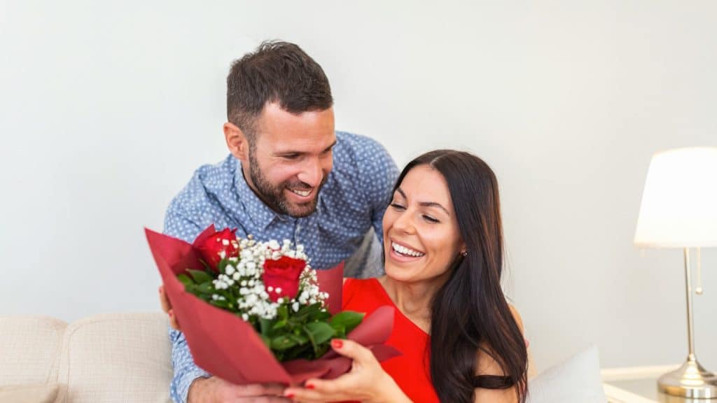 A man giving his wife a bouquet of flowers in order to appreciate her.