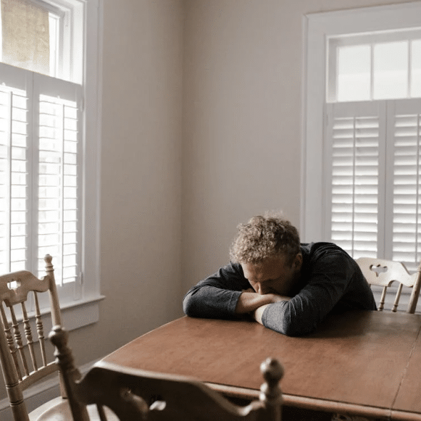 Man in Gray Long Sleeve Shirt Sitting on Brown Wooden Chair
