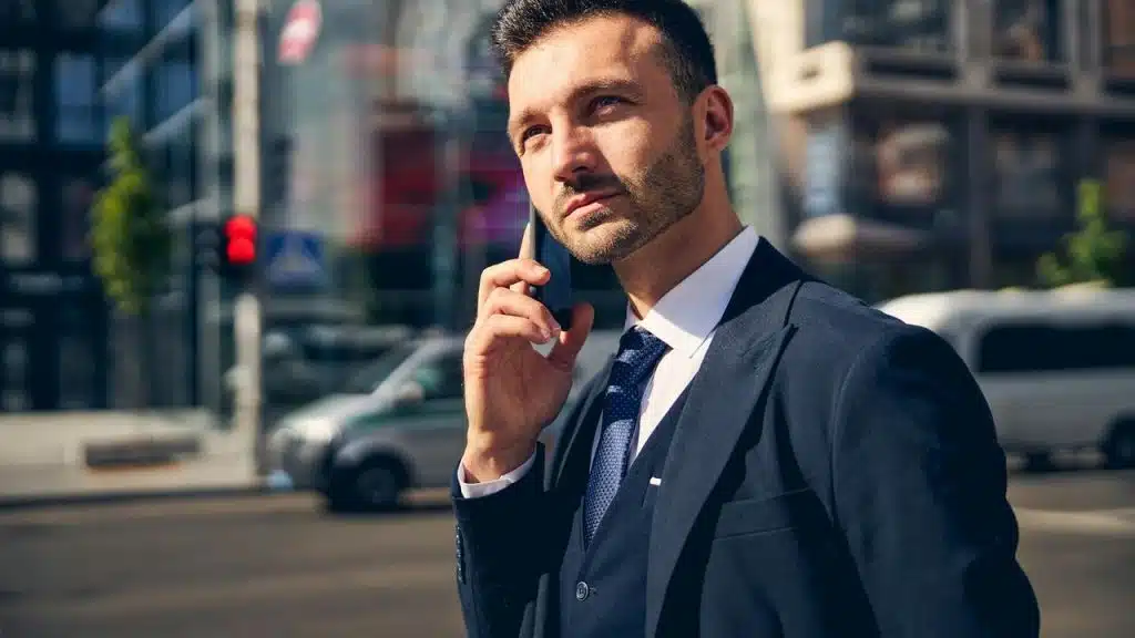 A man in a suit talking on a phone outdoors.