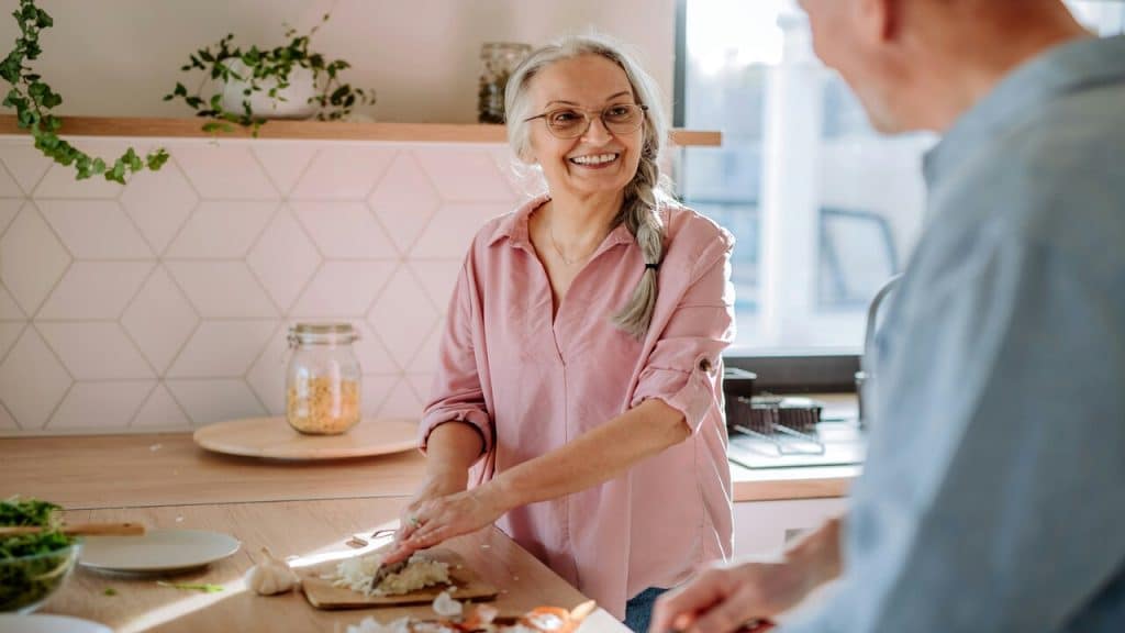 A couple smiling at each other in the kitchen