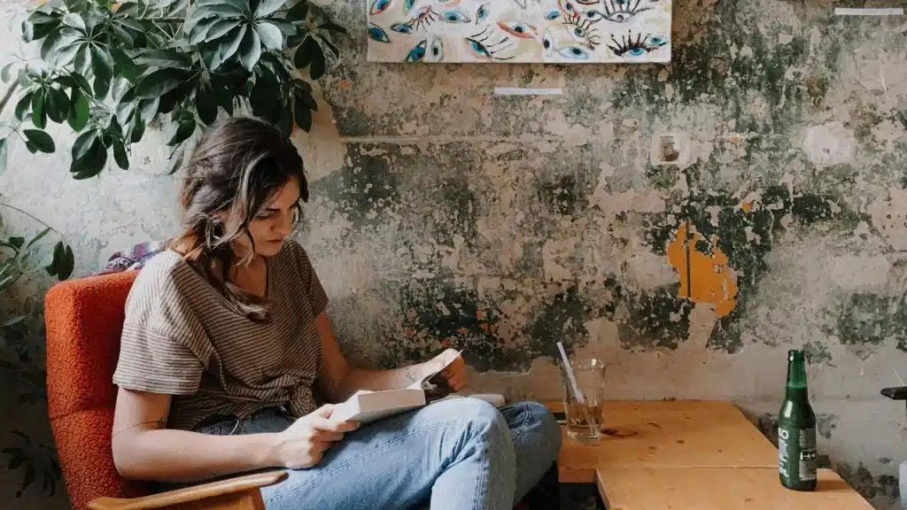 A woman sitting in a cozy room reading a book.