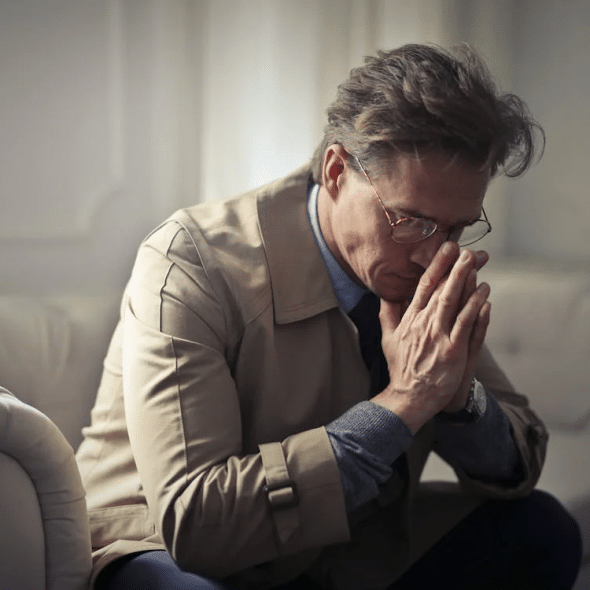 Sad mature businessman thinking about problems in living room