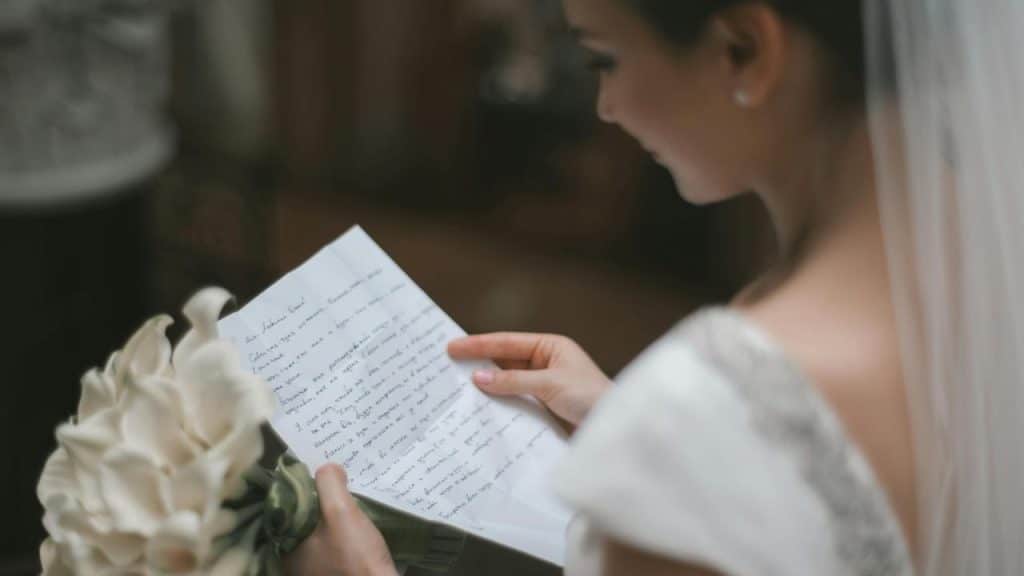 A bride holding flowers reads a handwritten letter.