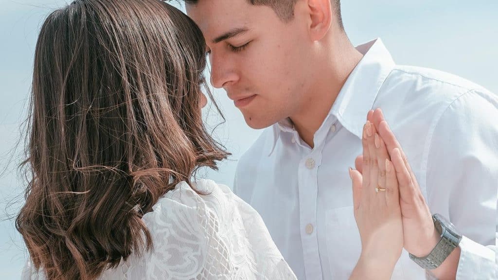 A couple shares a tender moment, gently touching foreheads while standing close together.
