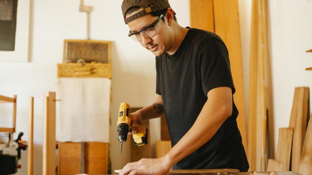 A person using a power drill while working on wood.