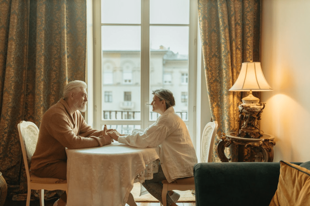 Couple Holding Hands while Sitting Next to the Glass Window