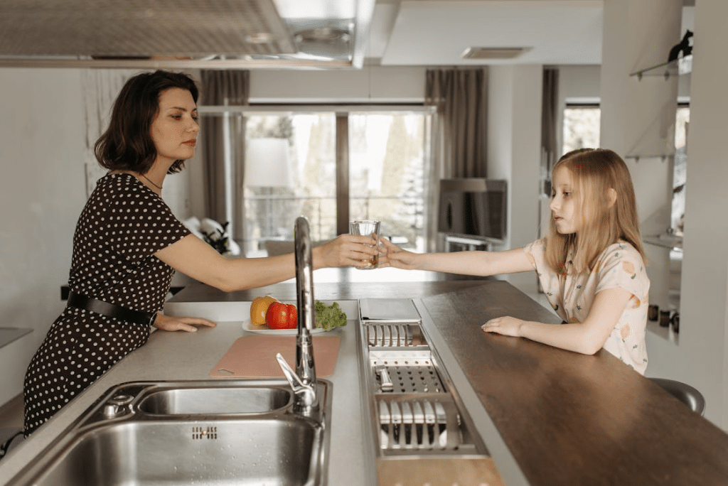 A woman passing a drink to a child