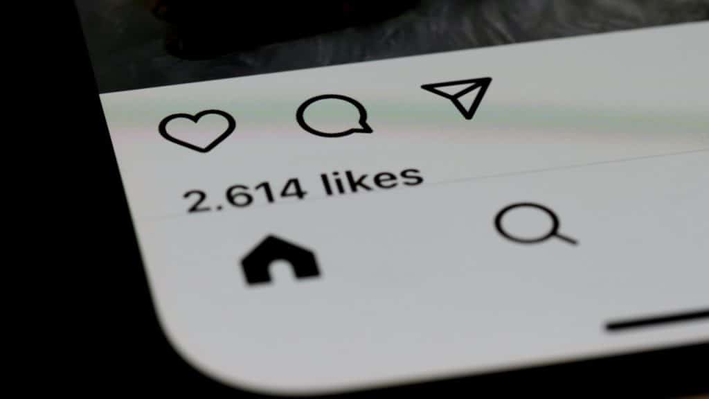 A close-up of a smartphone screen showing social media icons and a text reading "2,614 likes."