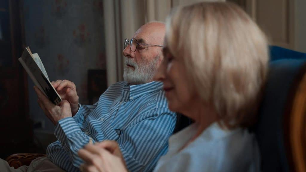 An older man reading beside a woman whoโs smiling contentedly.