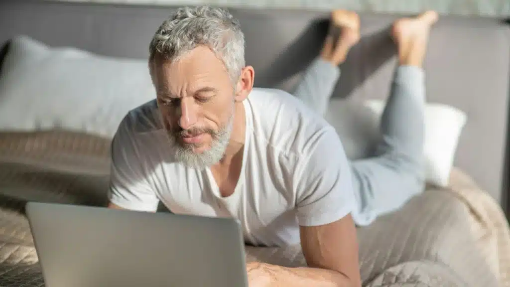 A middle aged man visiting online dating websites on a laptop.