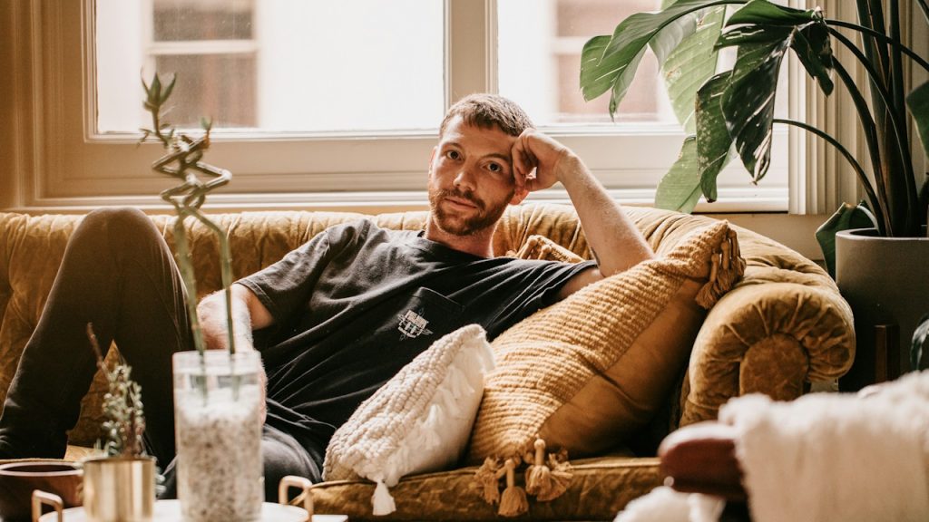 A man looking thoughtful while sitting on a couch.