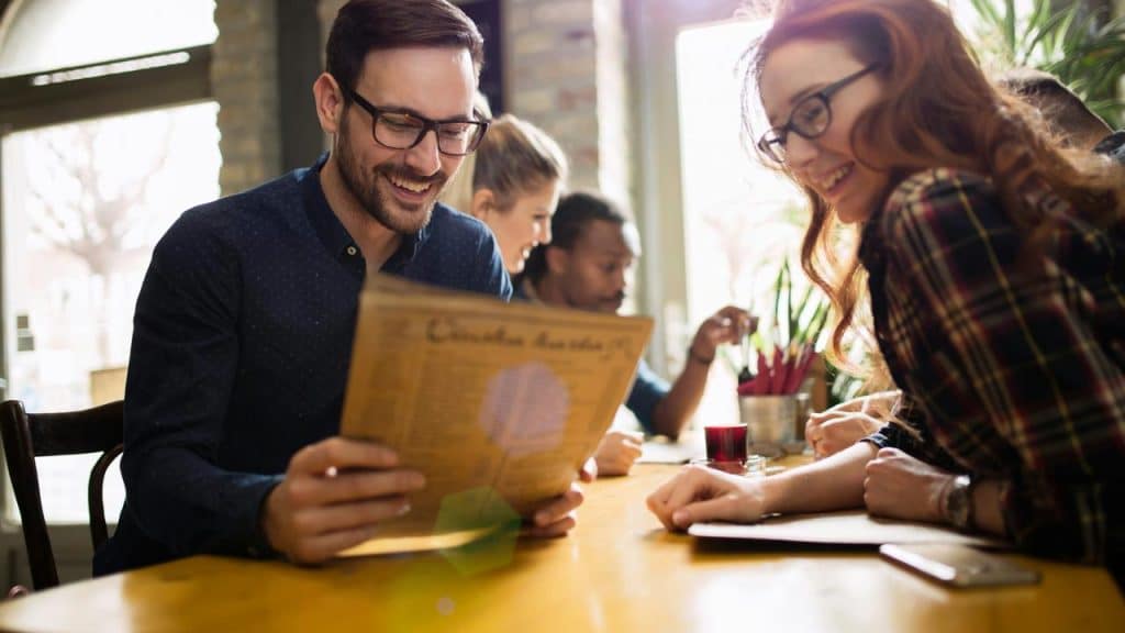 A couple smiling and looking at the menu together.