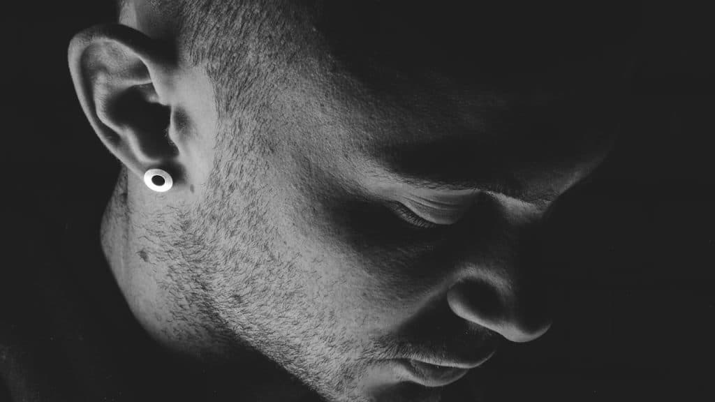 A man wearing an earring and looking depressed.