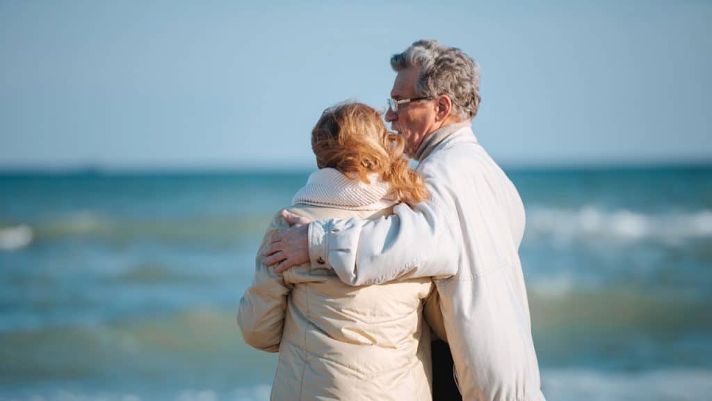Senior couple hugging while looking out at the ocean.