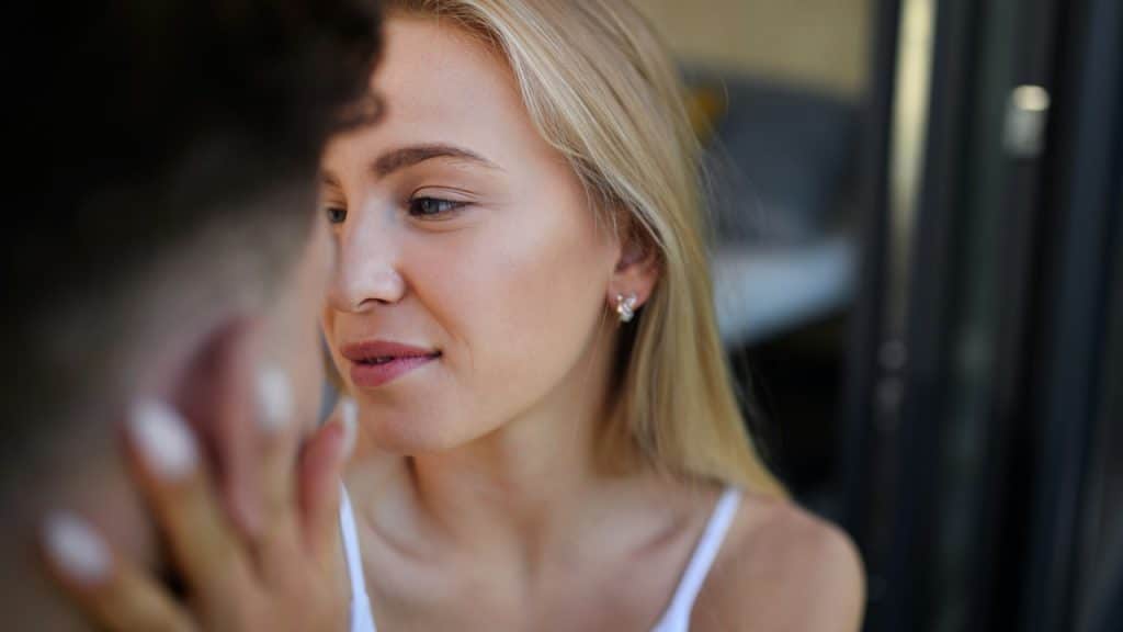 A woman stroking a man’s face and looking lovingly at him.