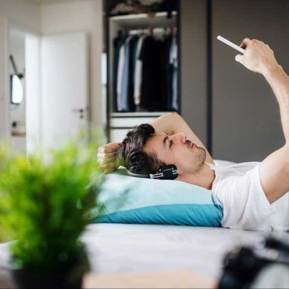 A man laying in bed while using a phone