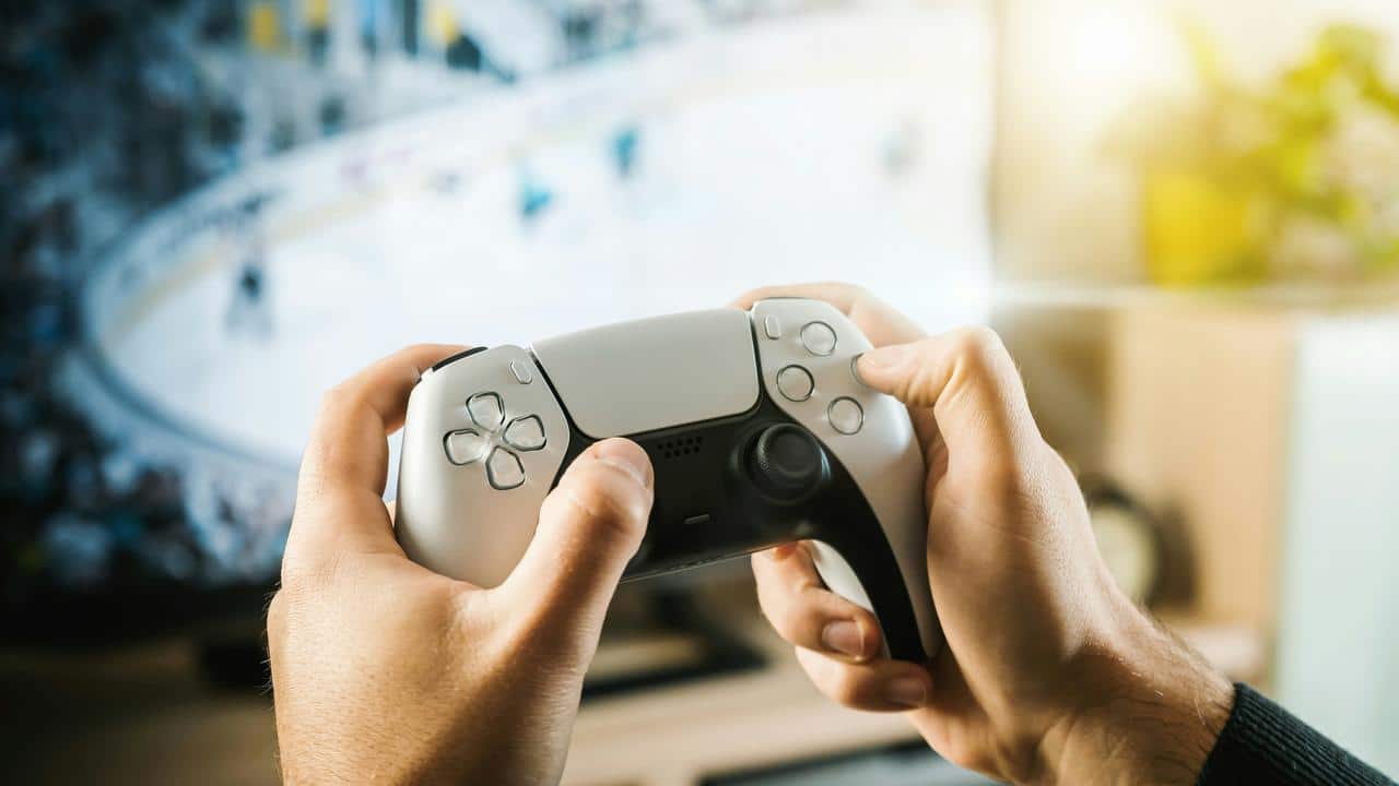 A person holding a game controller while playing on a TV.