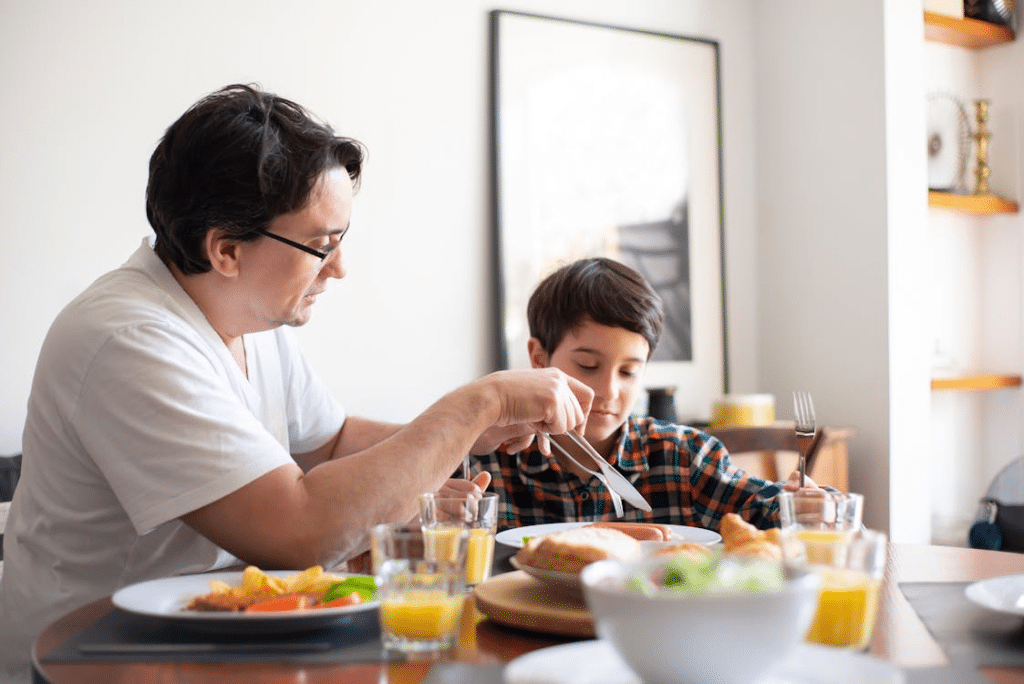 A Man and A Young Boy Eating on Dining Table