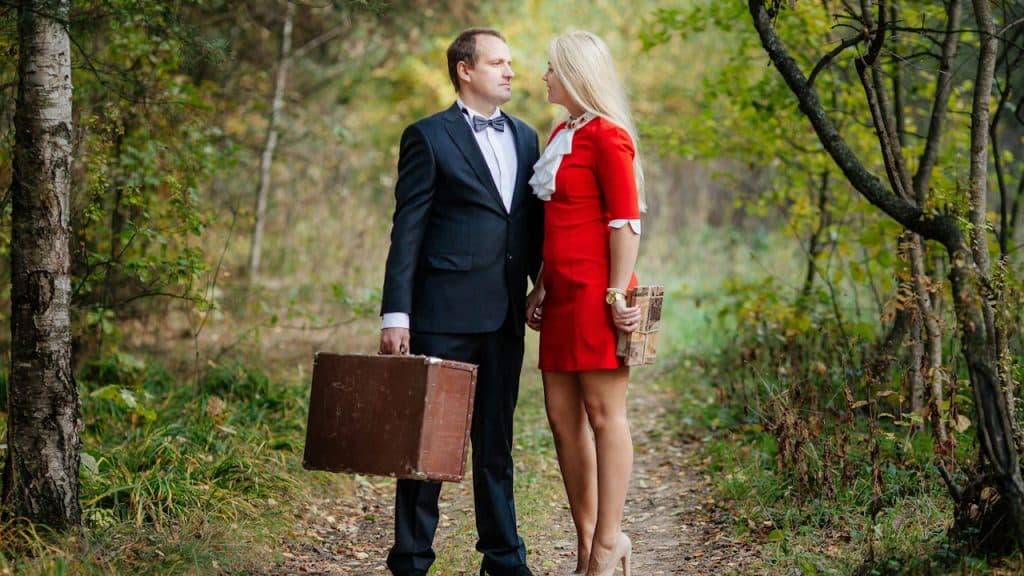 A man and woman walking on a path in the woods.
