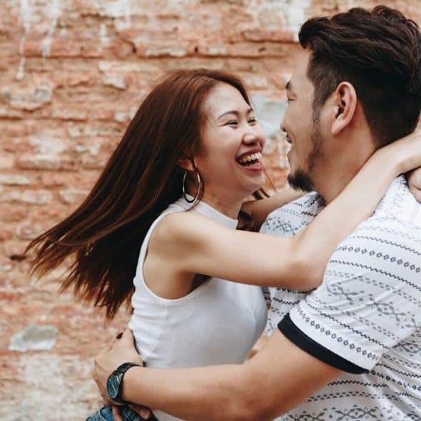 A woman smiling and hugging a man.