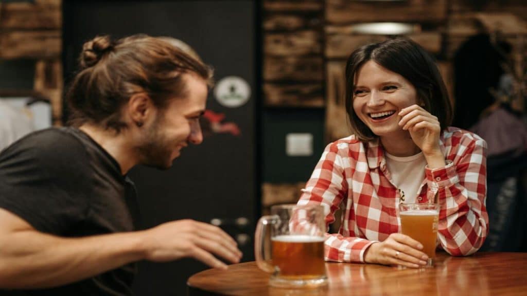 A couple laughing while having beer together