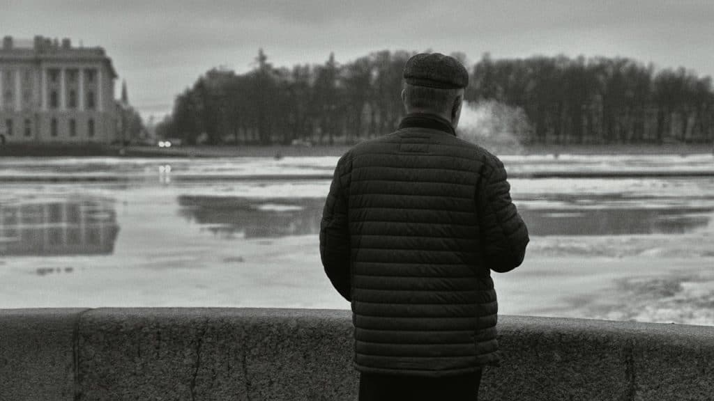 A man standing on wall looking at a body of water.